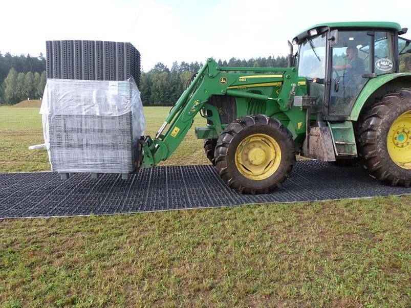 Tractor carrying a pallet driving over EcoGrid ground reinforcement panels