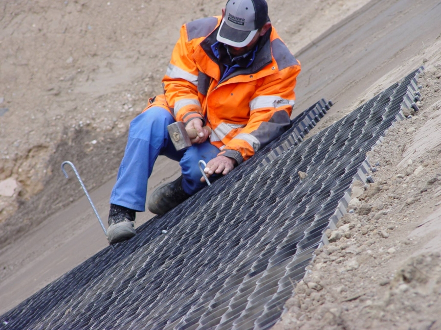 Contractor installing EcoGrid ground reinforcement on a steep embankment for slope stabilisation