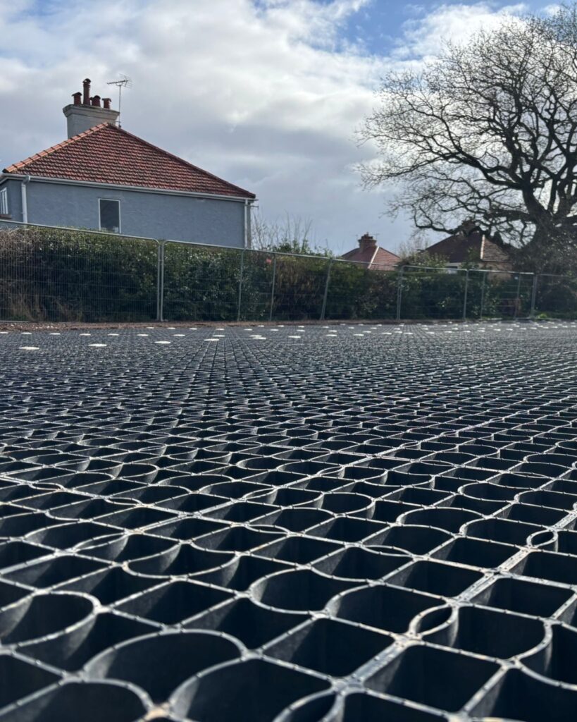 Close-up of EcoGrid permeable paving grids installed on a car park, showing the interlocking cell structure before being filled with gravel